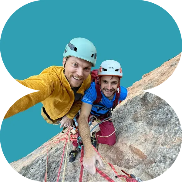 Two climbers looking up at the camera from a granite slab, ropes running down the rock.