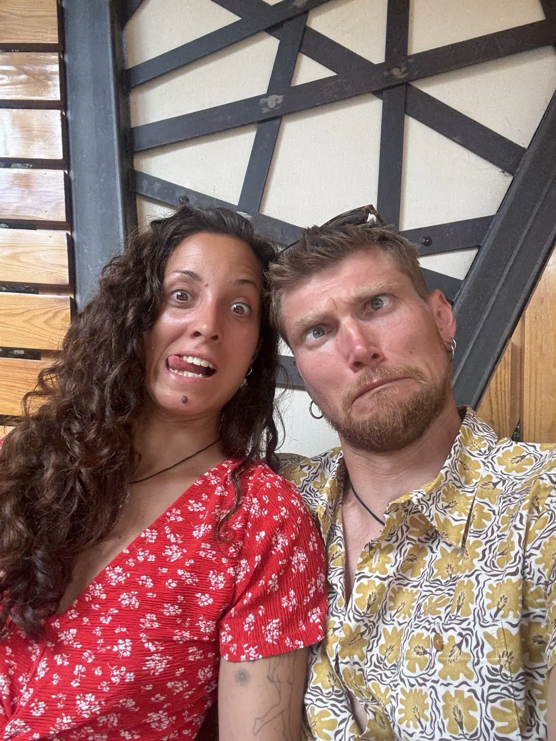 Carmen and Charlie squashed together on a staircase, both pulling deliberately ridiculous faces at the camera.