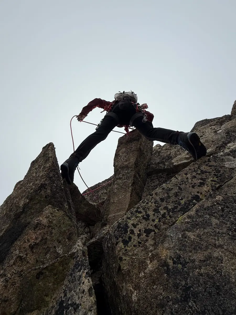 A climber pulling through a steep roof, silhouetted against a pale sky.