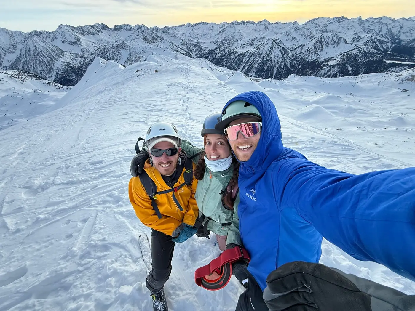 Three of us on a snowy summit ridge, snow-covered peaks running to the horizon behind.