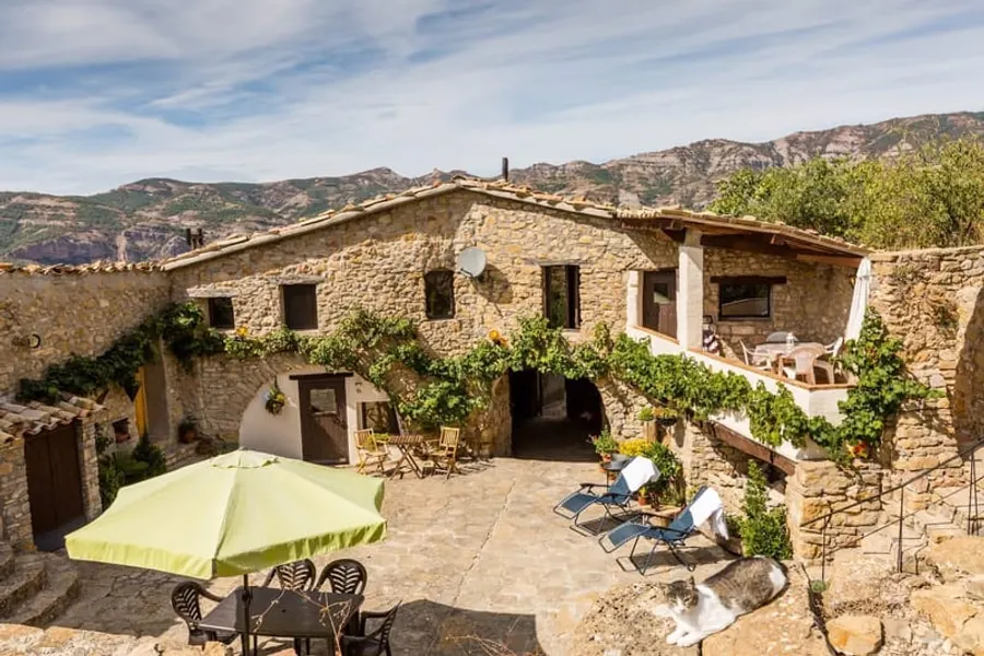 The front of the house, vines along the wall and a table out in the courtyard.
