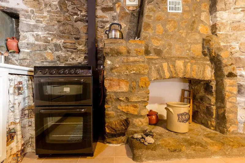 The kitchen, with the oven set into an old stone fireplace.