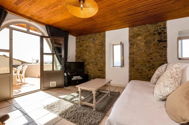 The living room, with an arched door standing open onto the terrace and the valley beyond.