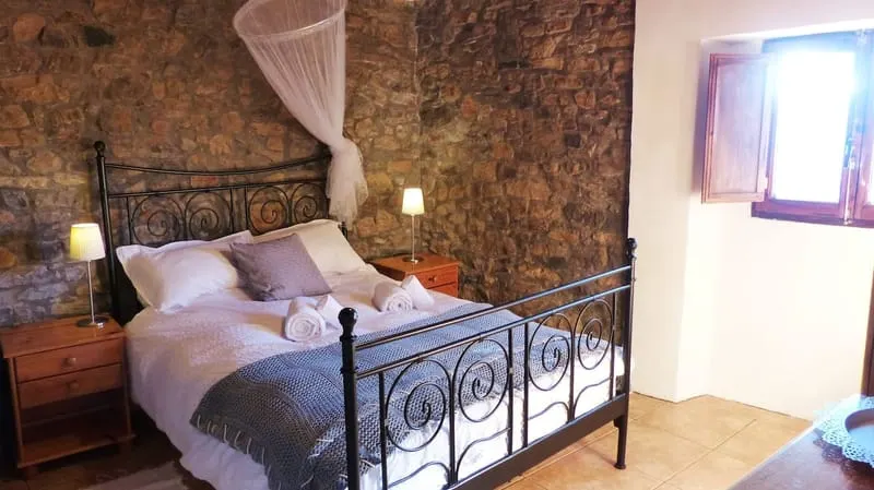 One of the two double bedrooms, an iron bed against a bare stone wall.
